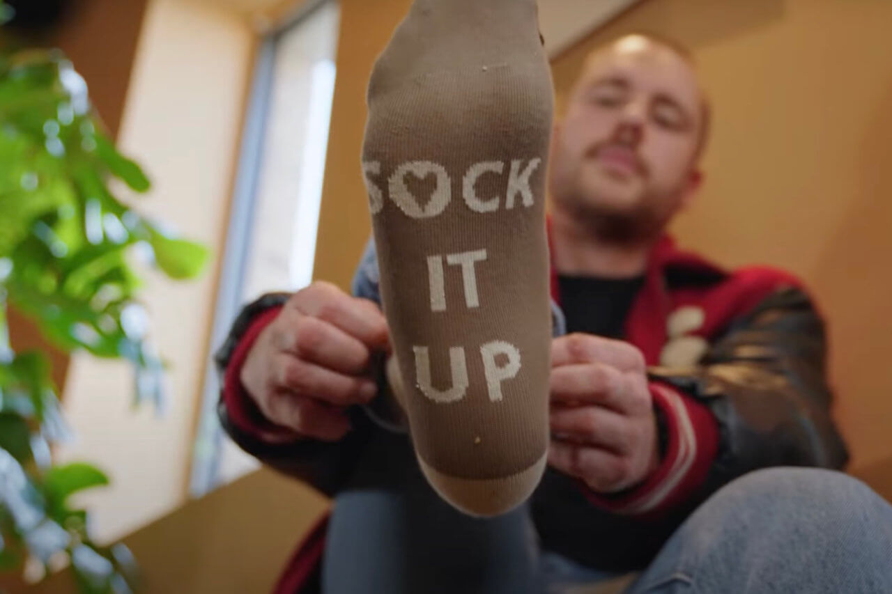 Een man trekt een Bagels & Beans Sock It Up sok aan.